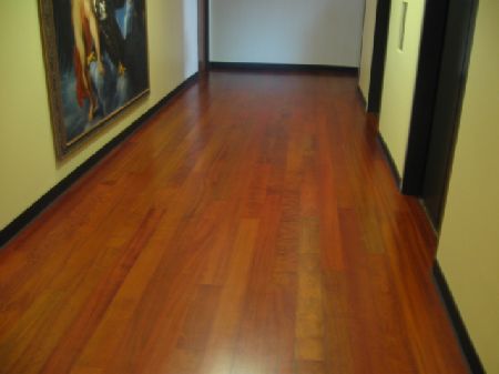 Reddish-brown Brazilian cherry hardwood floor in a commercial corridor with framed artwork on the walls