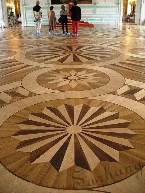 Large commercial parquet wood floor with ornate circular compass medallion patterns