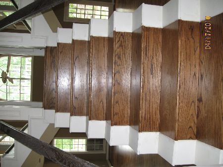 Custom oak stair treads with painted white risers rising to a landing with windows in a Houston home