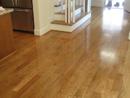 Golden oak hardwood floor installed in a Houston kitchen with a staircase