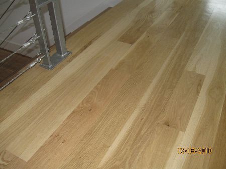Pale natural white oak hardwood floor with a clear water-base finish beside a cable stair rail in Houston